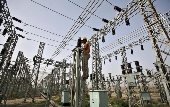 An employee works on electric pylons at a power station in Greater Noida